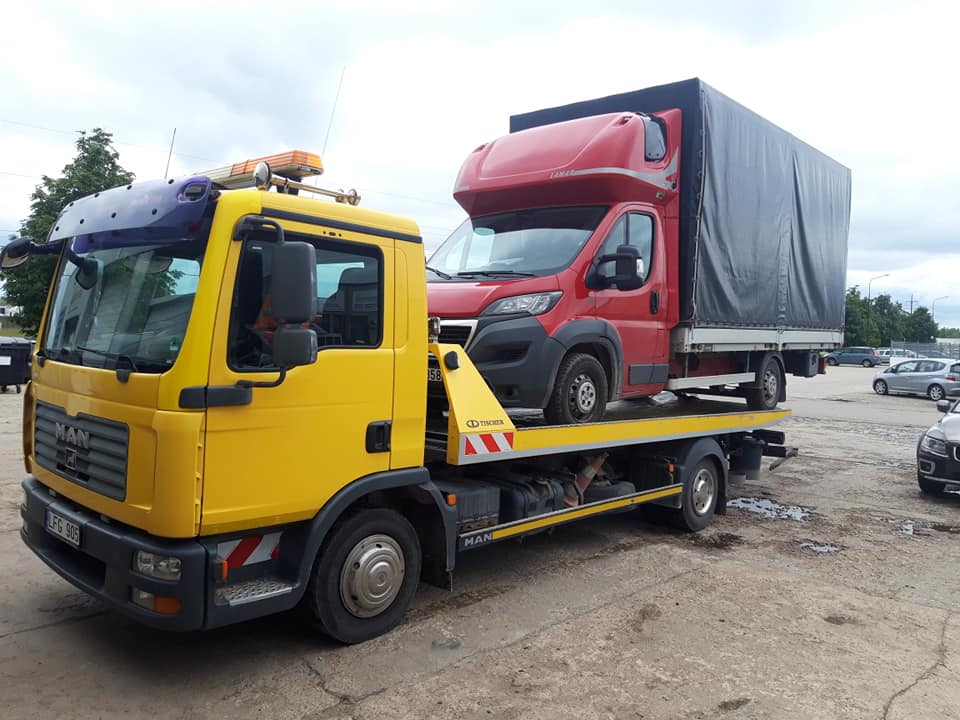 Mikroautobusas pakrautas kroviniais ant platforminio tralo