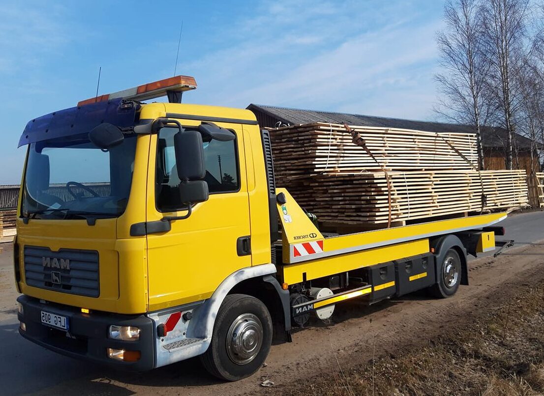 Platus platforminis tralas su pakrautomis statybinėmis medžiagomis