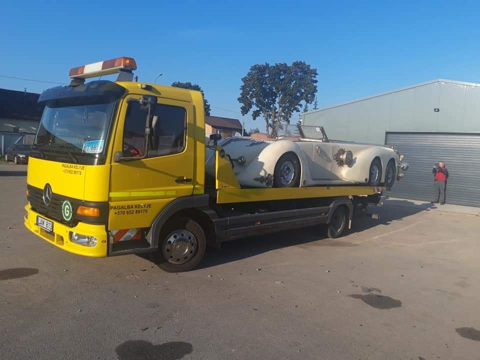 Lengvasis automobilis pakrautas ant platforminio tralo