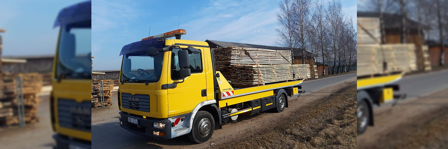 Platus platforminis tralas su pakrautomis statybinėmis medžiagomis